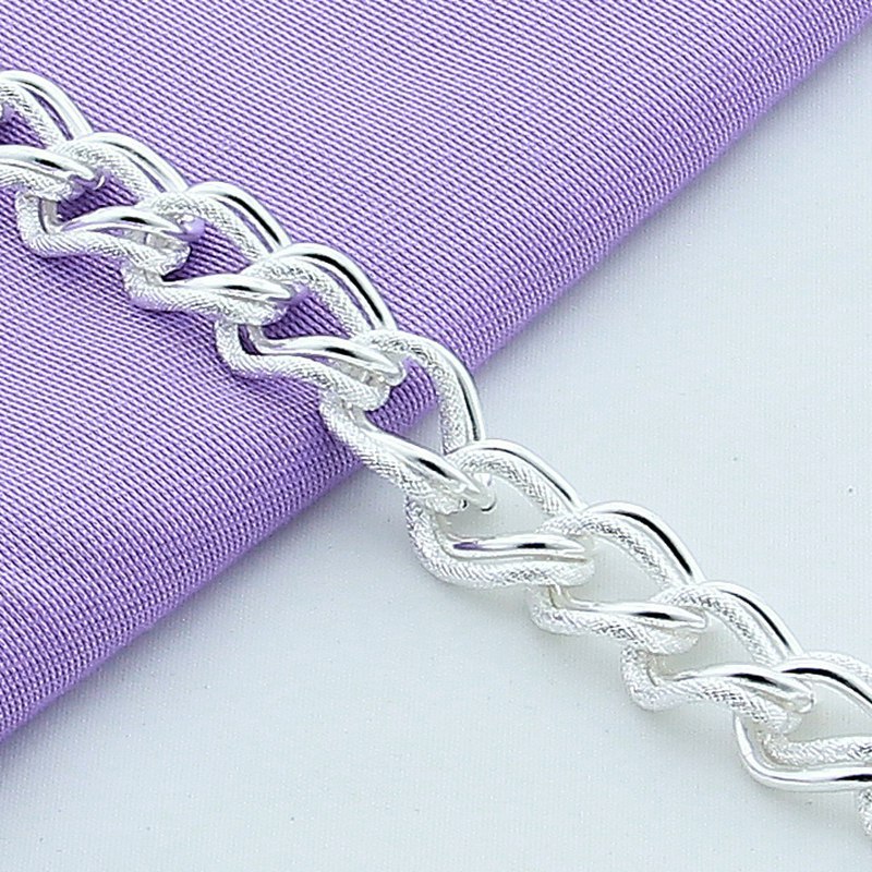 Silver chain bracelet on a purple fabric background