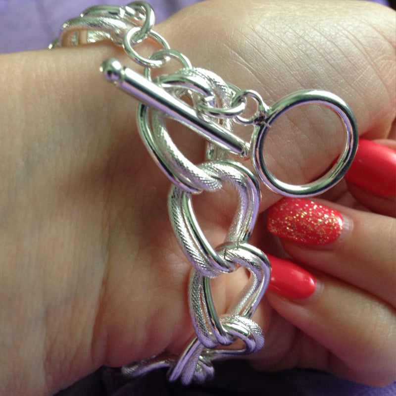 Silver bracelet on a hand with red nail polish